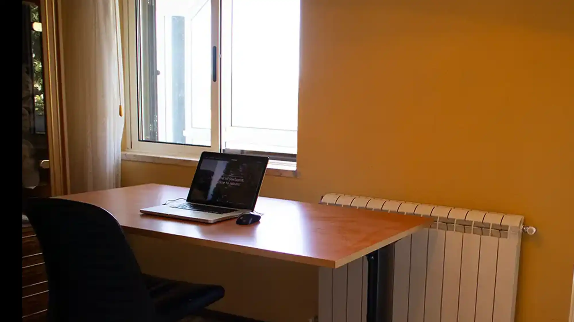 Bright co-working space with desks, laptop, and mountain views in the background.