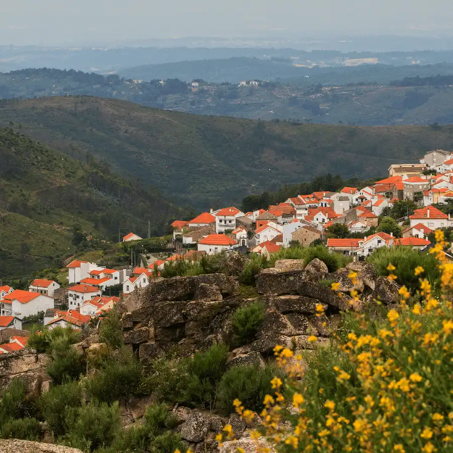 Aldeia montanhosa com encanto, telhados de barro e vistas serenas.